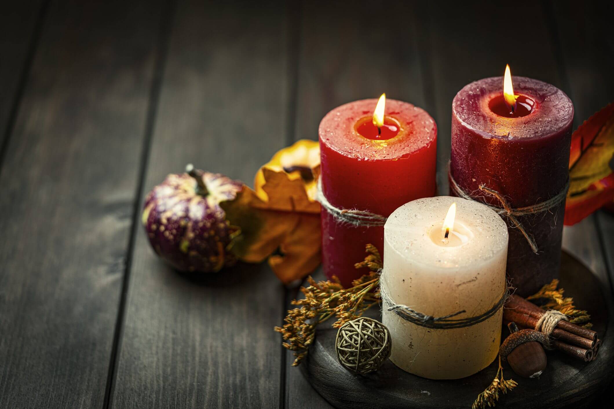 Three candles with autumn decorations on table.