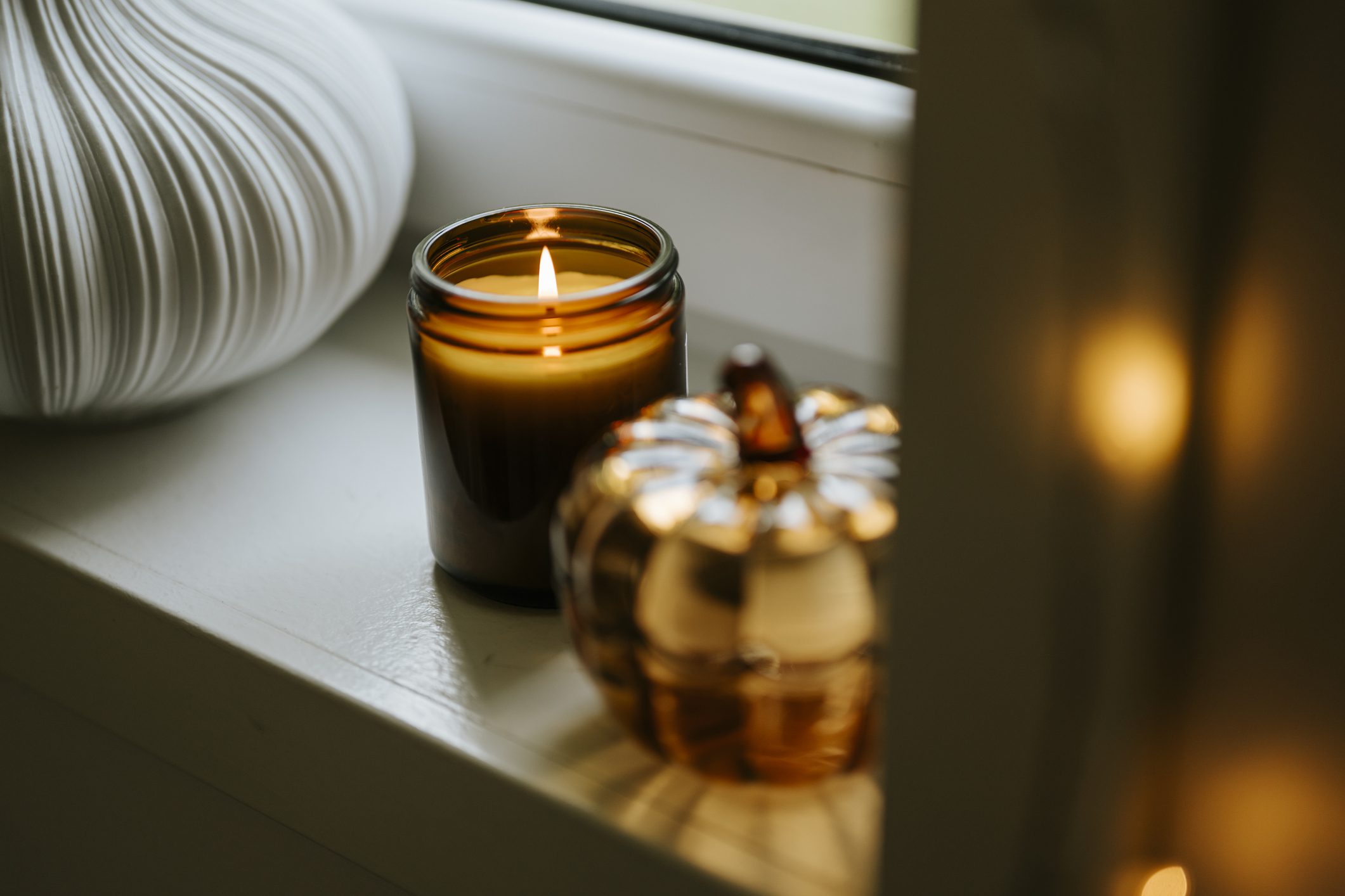 Candle and pumpkin decoration on windowsill.