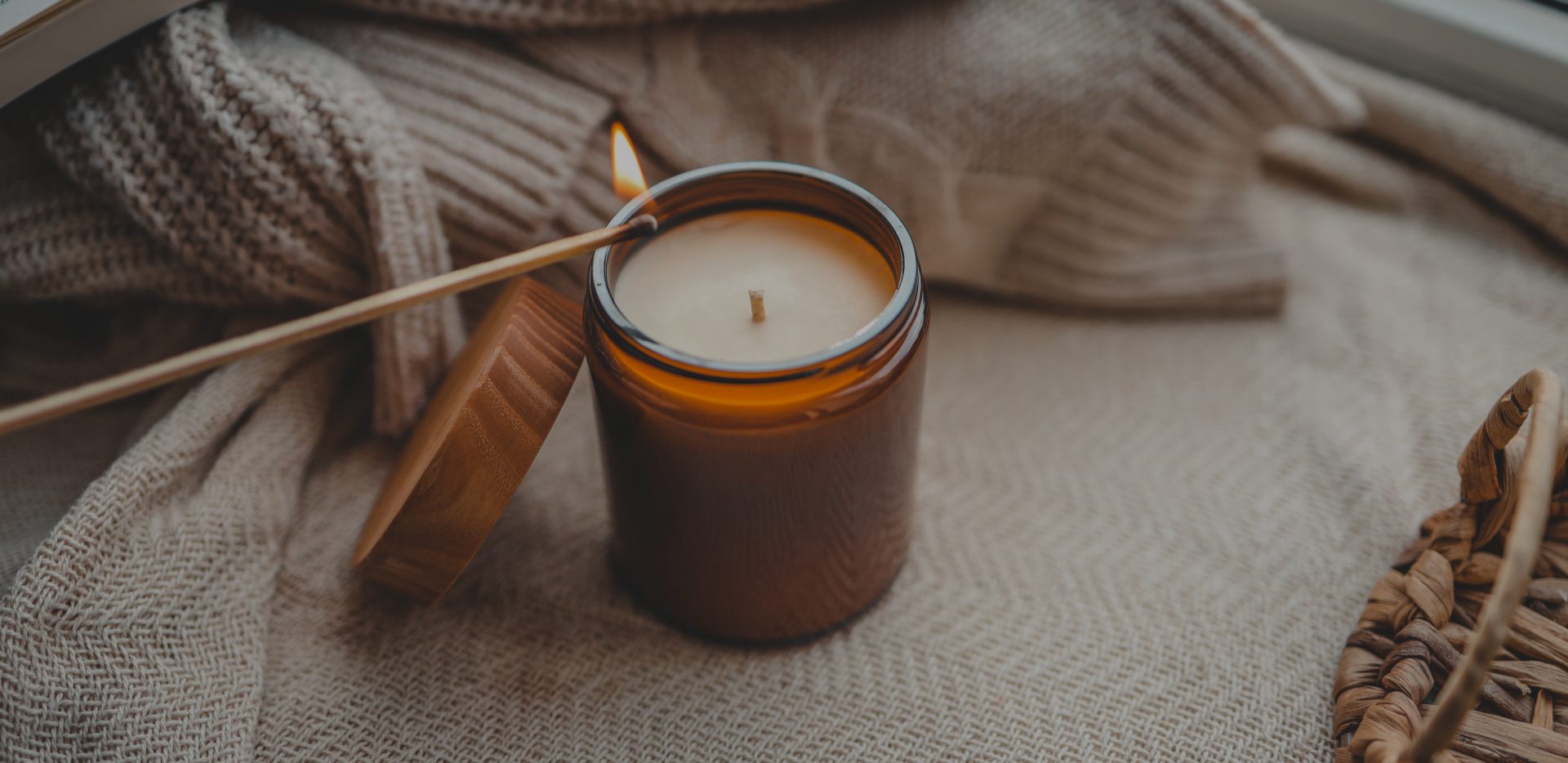 Lit candle on cozy knitted blanket.