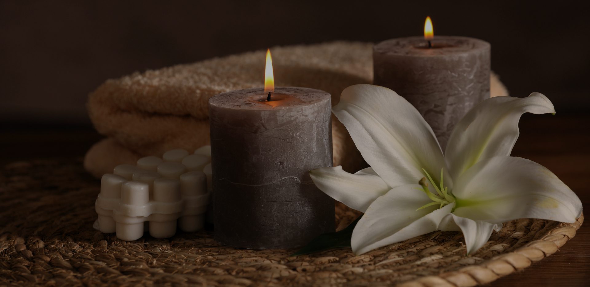 Lit candles with lily and towels.